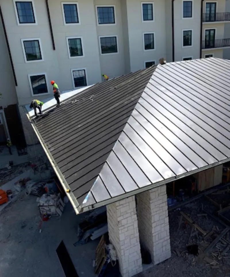 Crew installing standing seam metal roof panels on a commercial project in Linden